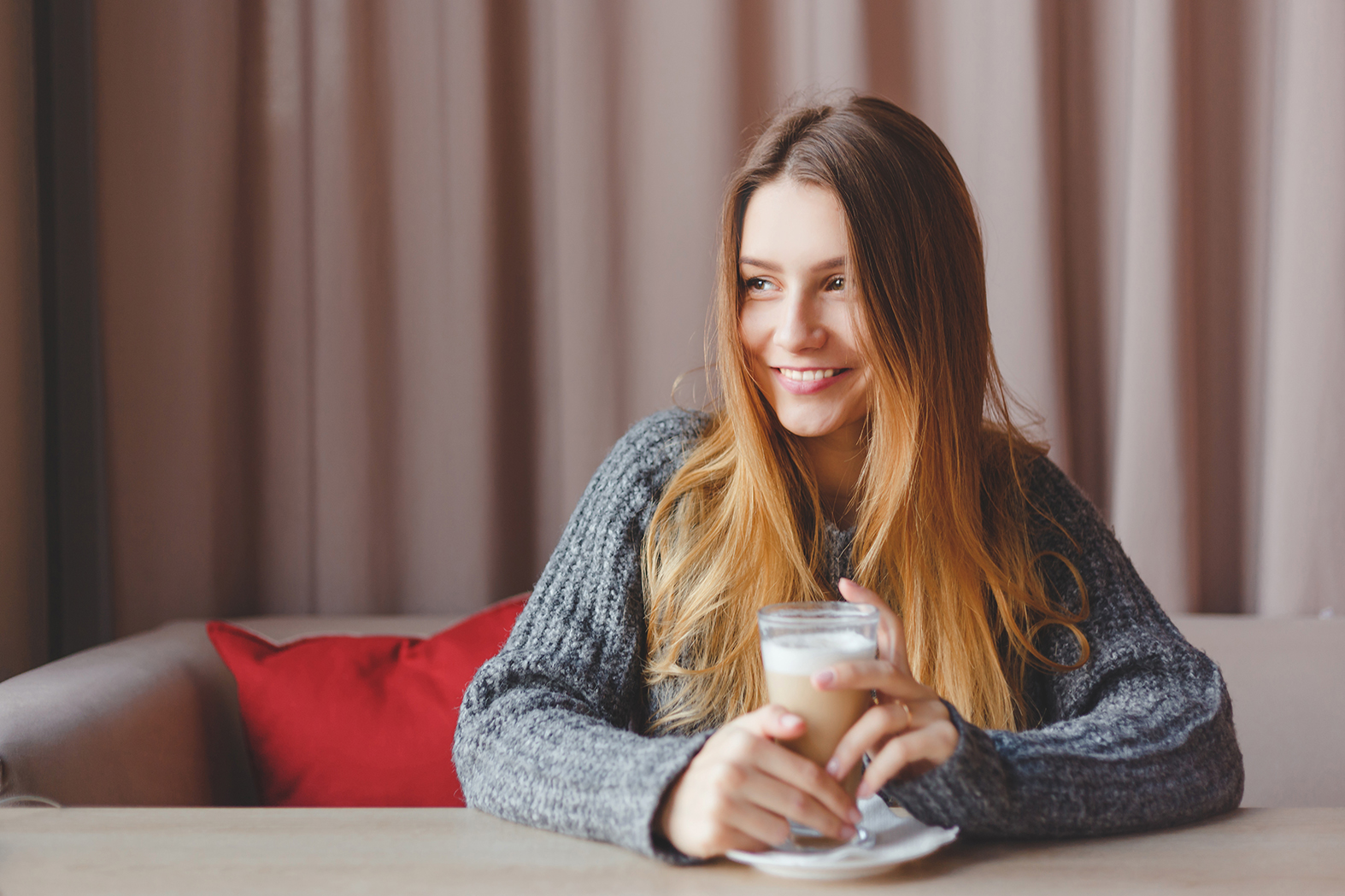 girl in knitted sweater dreams with a cup of hot coffee